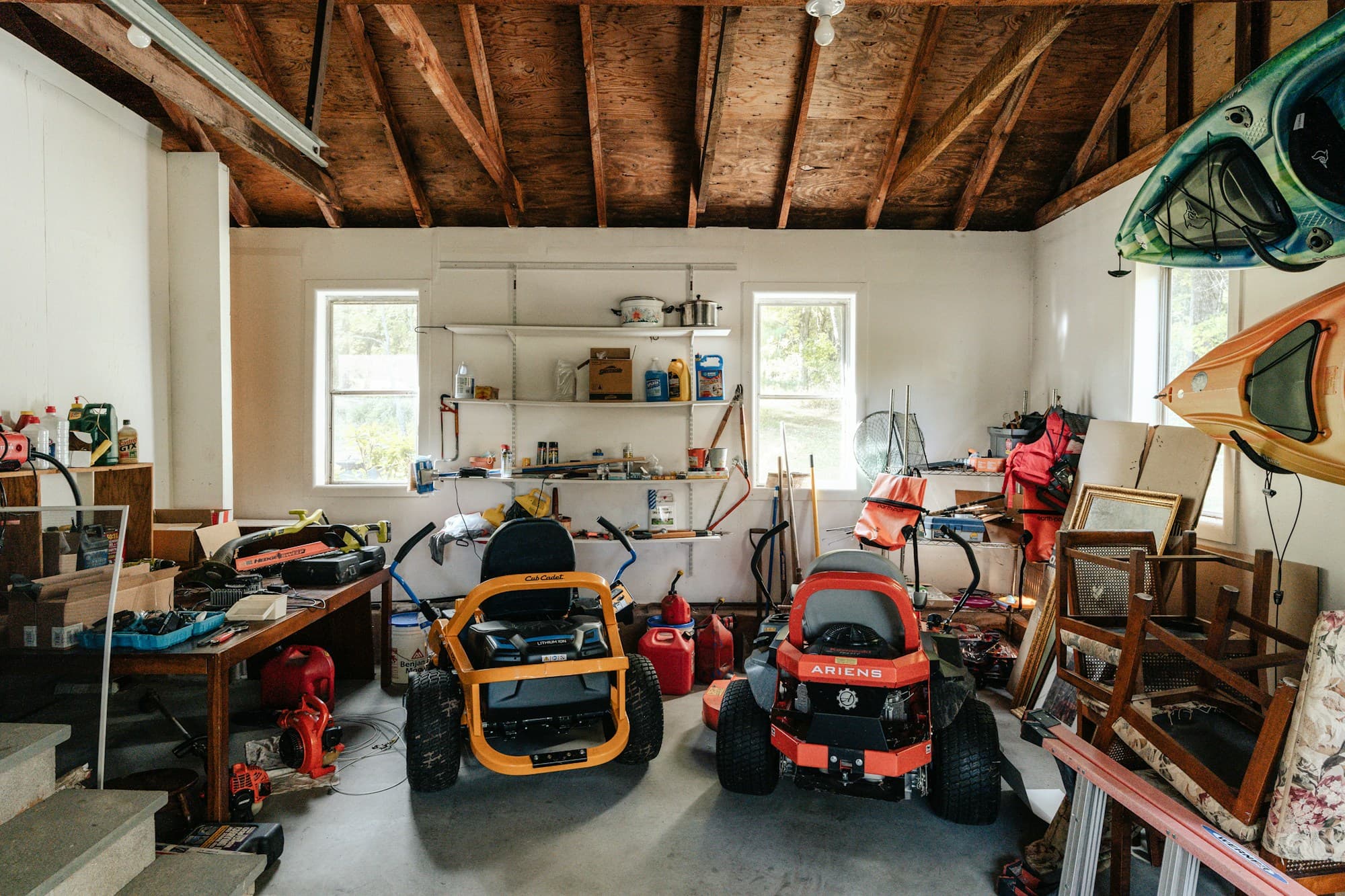 Home garage crowded with lawn equipment, kayaks and stored belongings