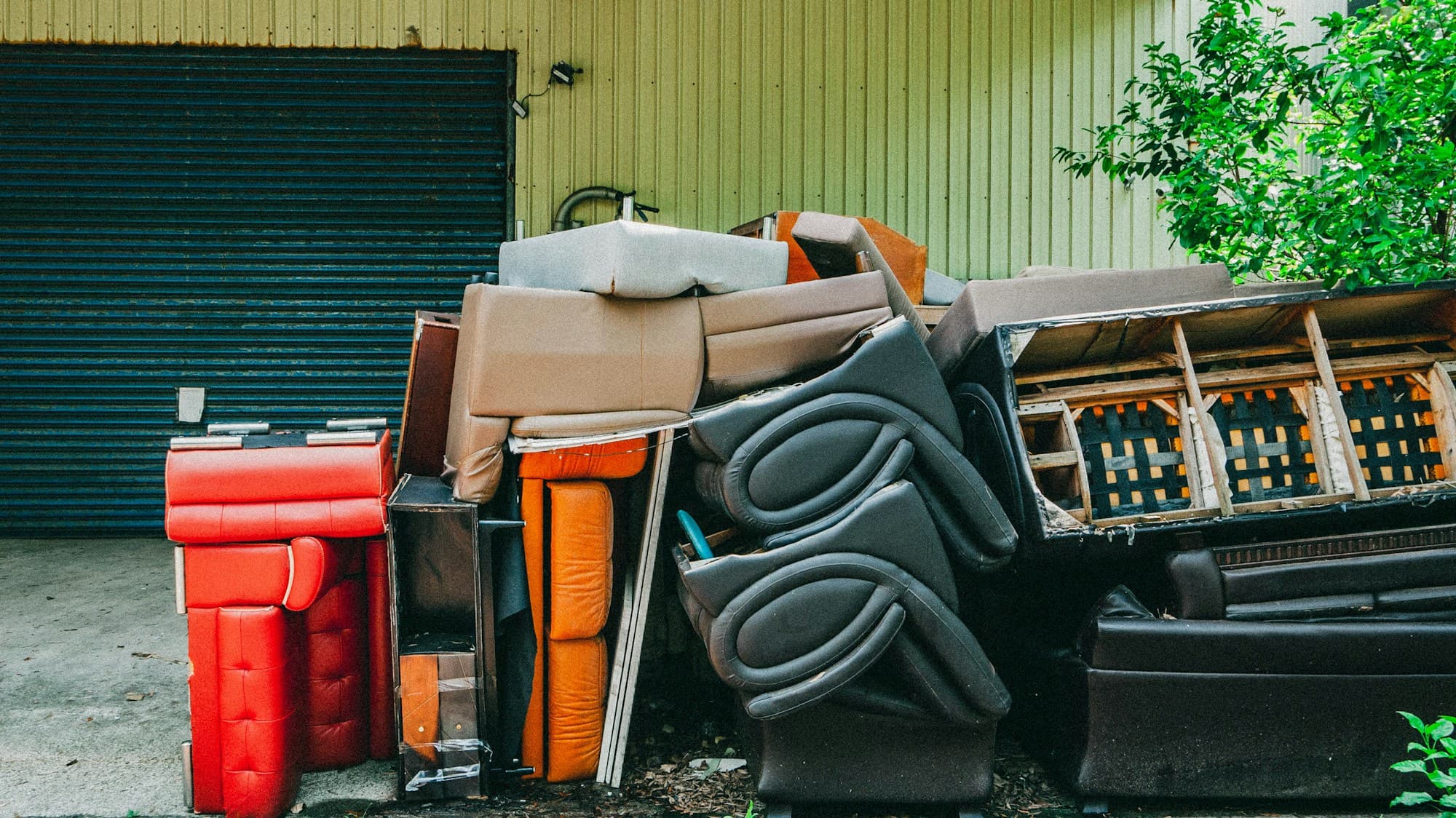 Large pile of discarded sofas, chairs and mattresses stacked outside during a property cleanout