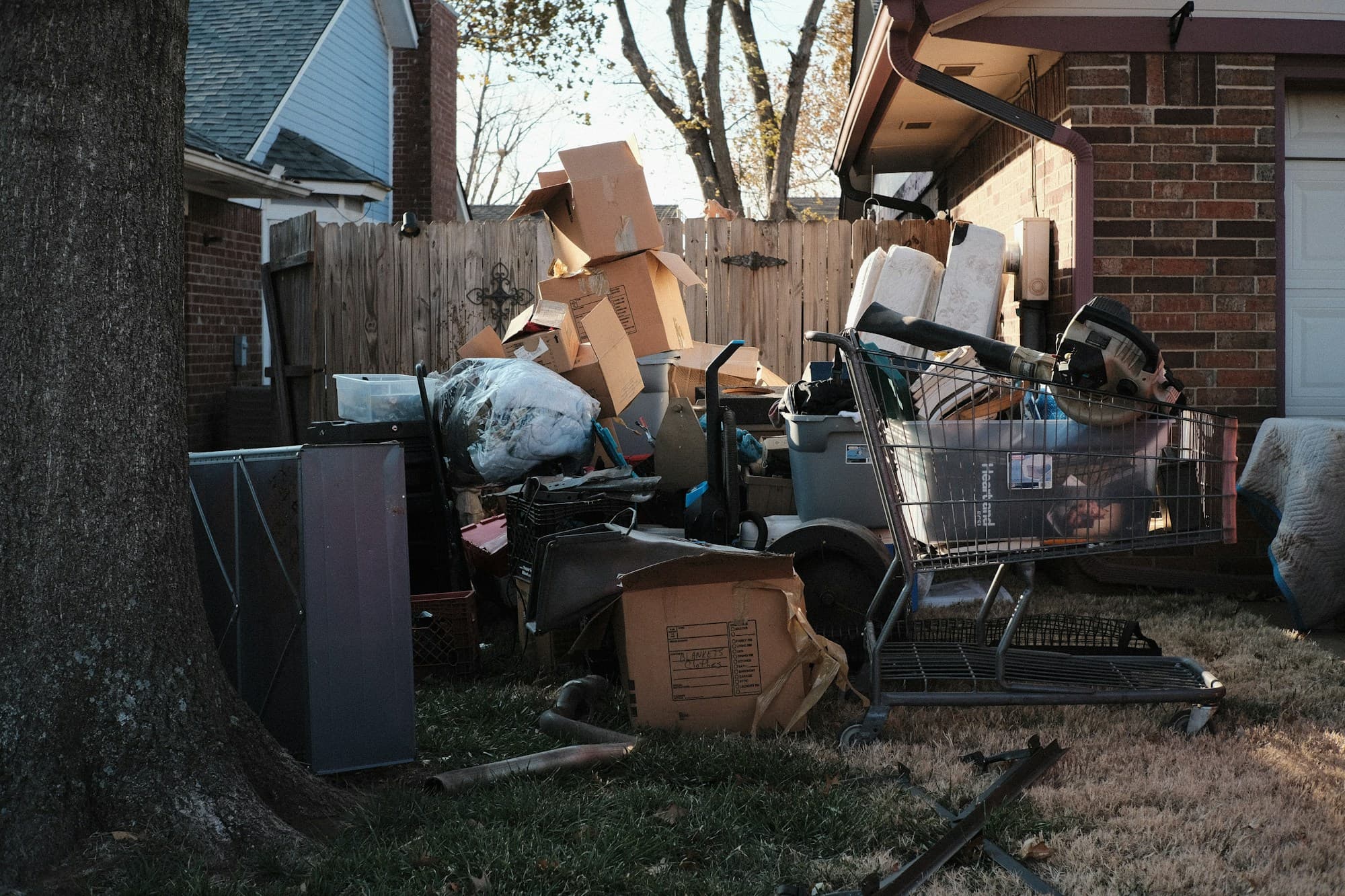 Pile of discarded furniture, boxes and appliances stacked beside a house awaiting removal