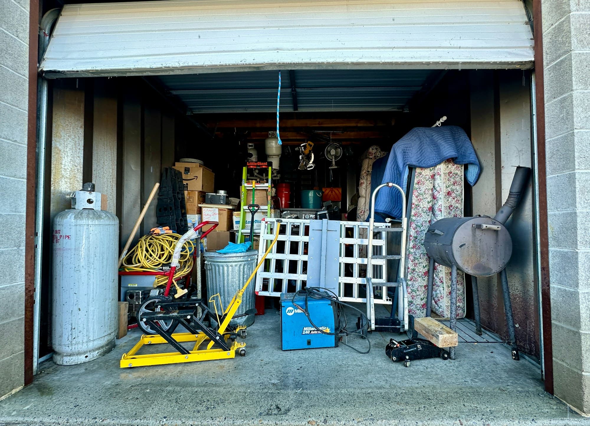 Residential garage packed floor to ceiling with stored household items before a cleanout
